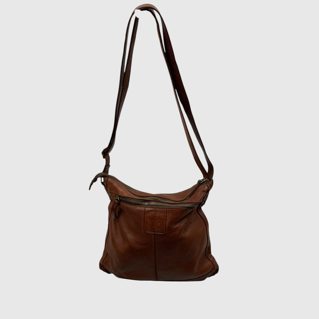 A brown leather shoulder bag with a long adjustable strap, a front zippered pocket, and a slouchy slouchy silhouette, shown against a plain light gray background.