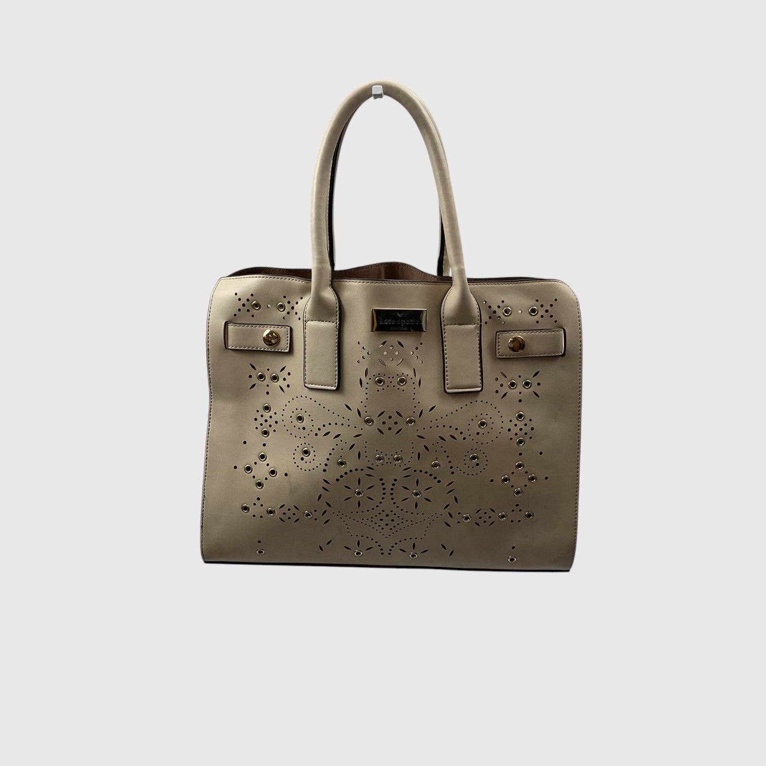A structured taupe leather handbag with laser-cut floral patterns, dual top handles, and gold-tone hardware, shown against a light gray background.