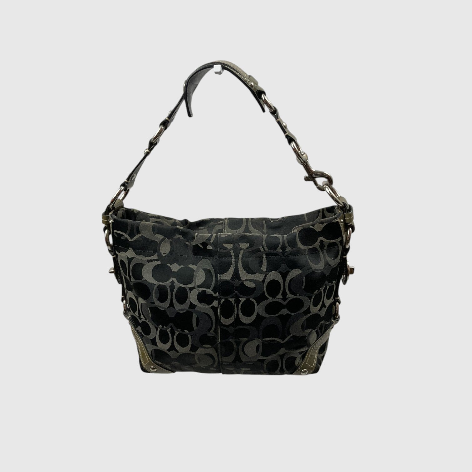 A Coach hobo shoulder bag in black coated canvas with the signature interlocking C logo pattern in dark gray and black, featuring a matching shoulder strap with chain details, shown against a light gray background.