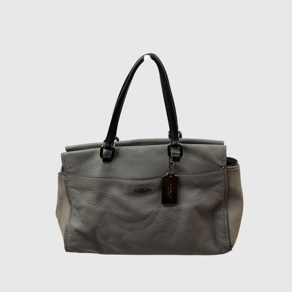  gray canvas tote bag with dark brown leather trim and shoulder strap, worn crossbody against a light gray studio background.