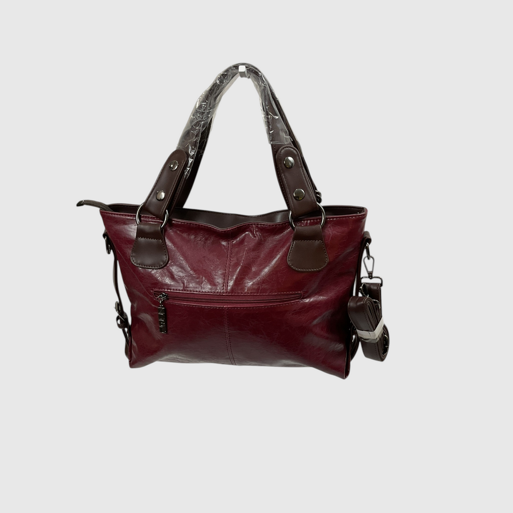 A burgundy leather handbag with dark brown leather handles and trim, featuring a front zippered pocket and a patterned top handle insert, shown against a light gray background.