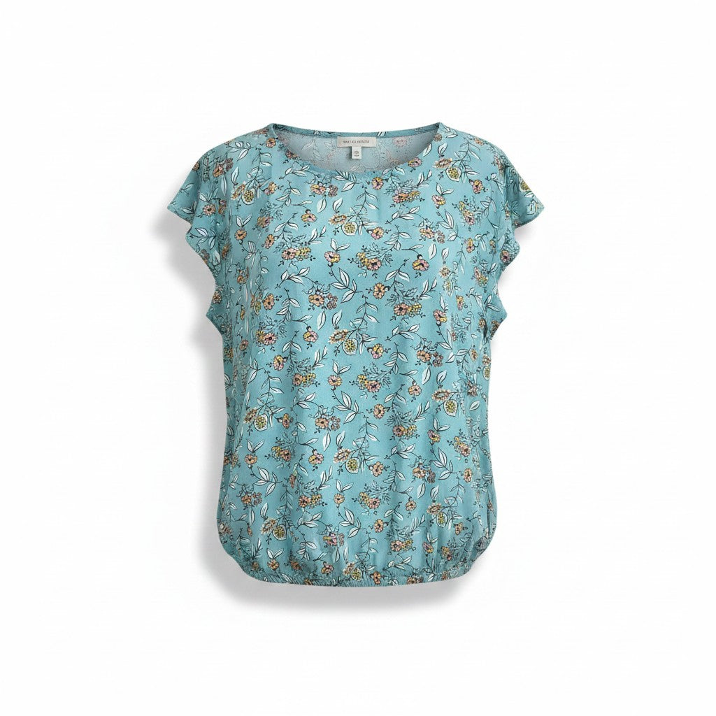 A women's short-sleeve blouse in a light teal blue color, featuring an all-over delicate floral and leaf print in muted orange, yellow, and white. The blouse has a relaxed, slightly gathered silhouette and a round neckline, shown flat against a white background.