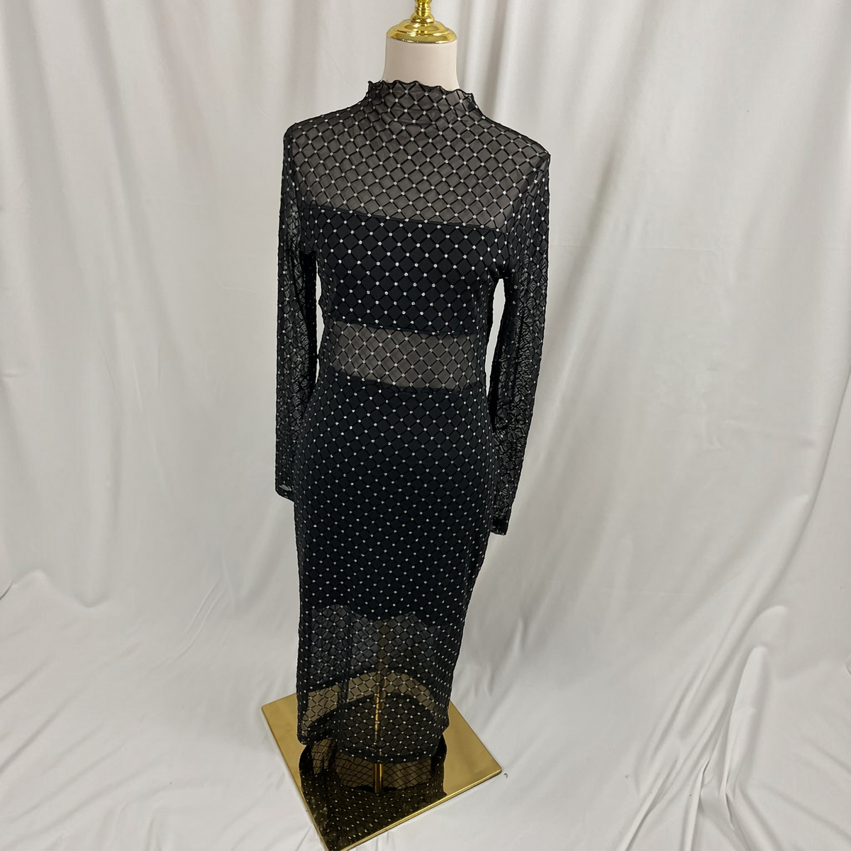 A black and gold geometric maxi dress on a light gray background