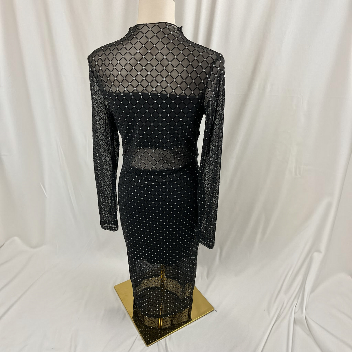 A black and gold geometric maxi dress on a light gray background