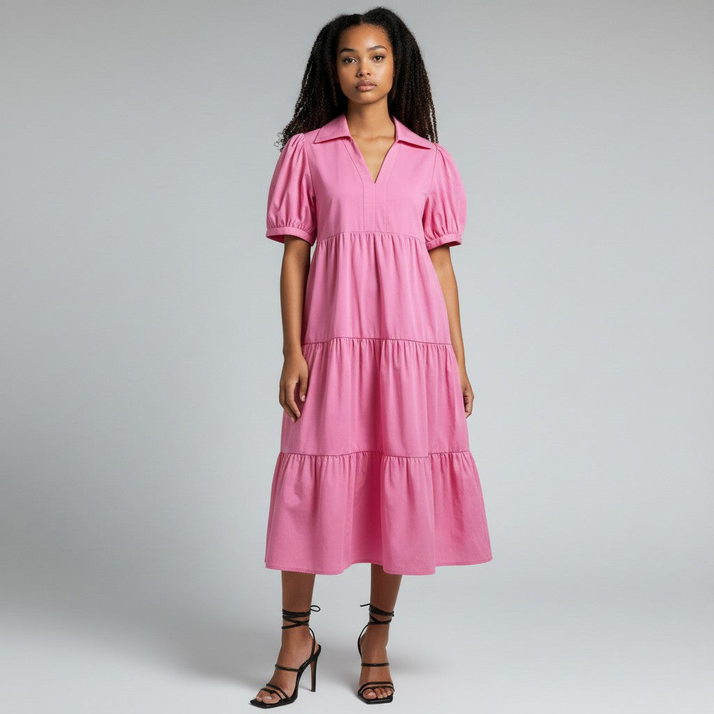 A woman wearing a pink dress with black heels on a light gray studio background