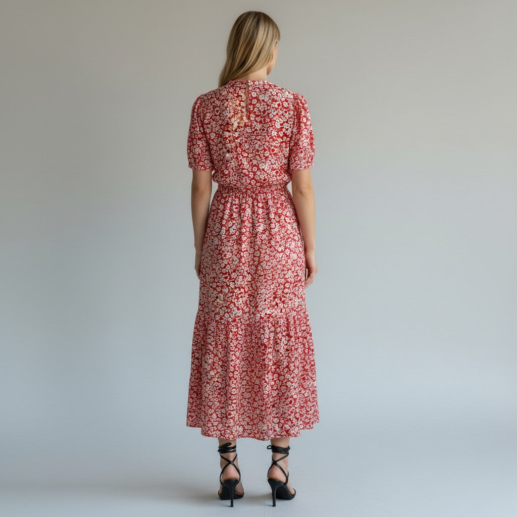 A woman in a red and white short sleeve dress and black heels on a light gray studio background.