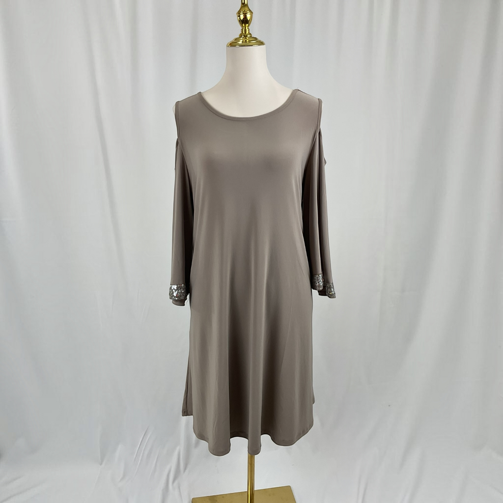 A woman with a dress and black heels on a light gray studio background.