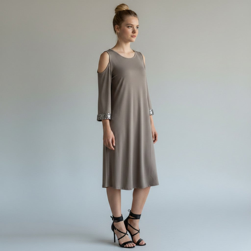A woman with a dress and black heels on a light gray studio background.