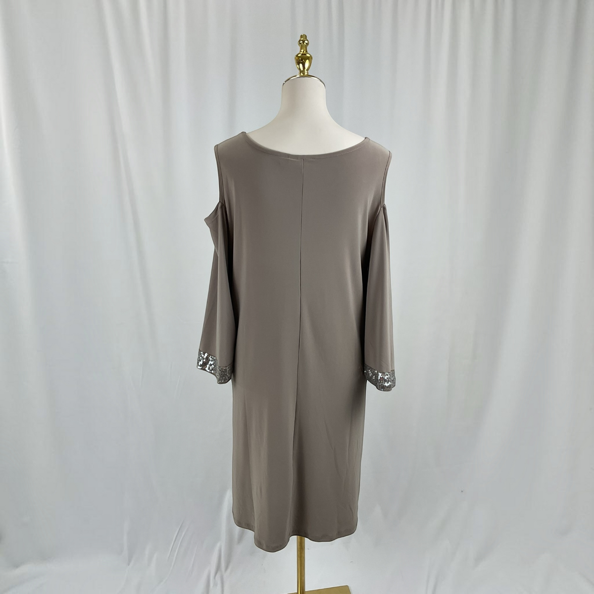 A woman with a dress and black heels on a light gray studio background.