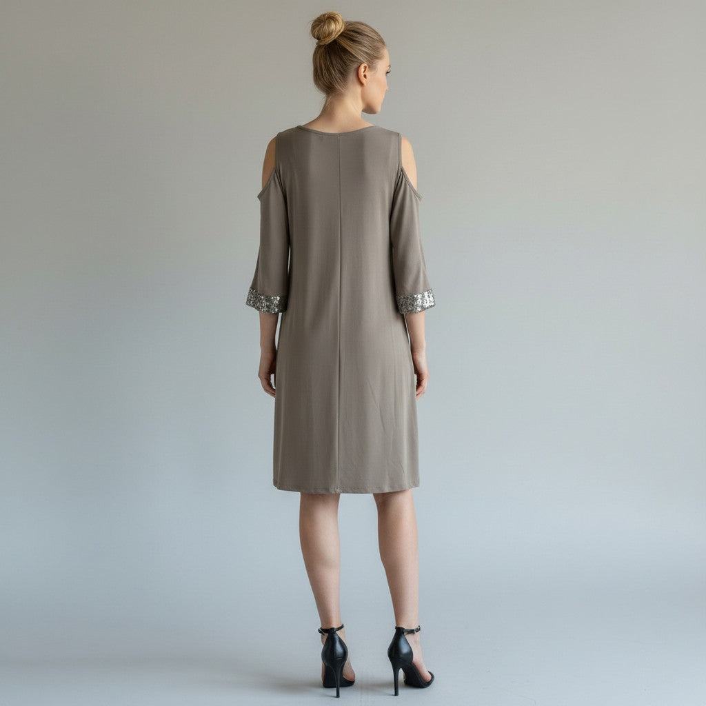 A woman with a dress and black heels on a light gray studio background.