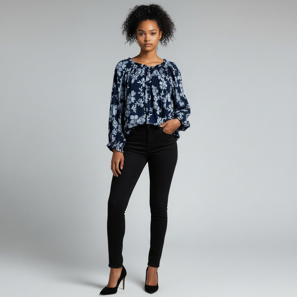 A woman with a blue and navy long sleeve shirt , black jeans , black high heels on a studio gray background.