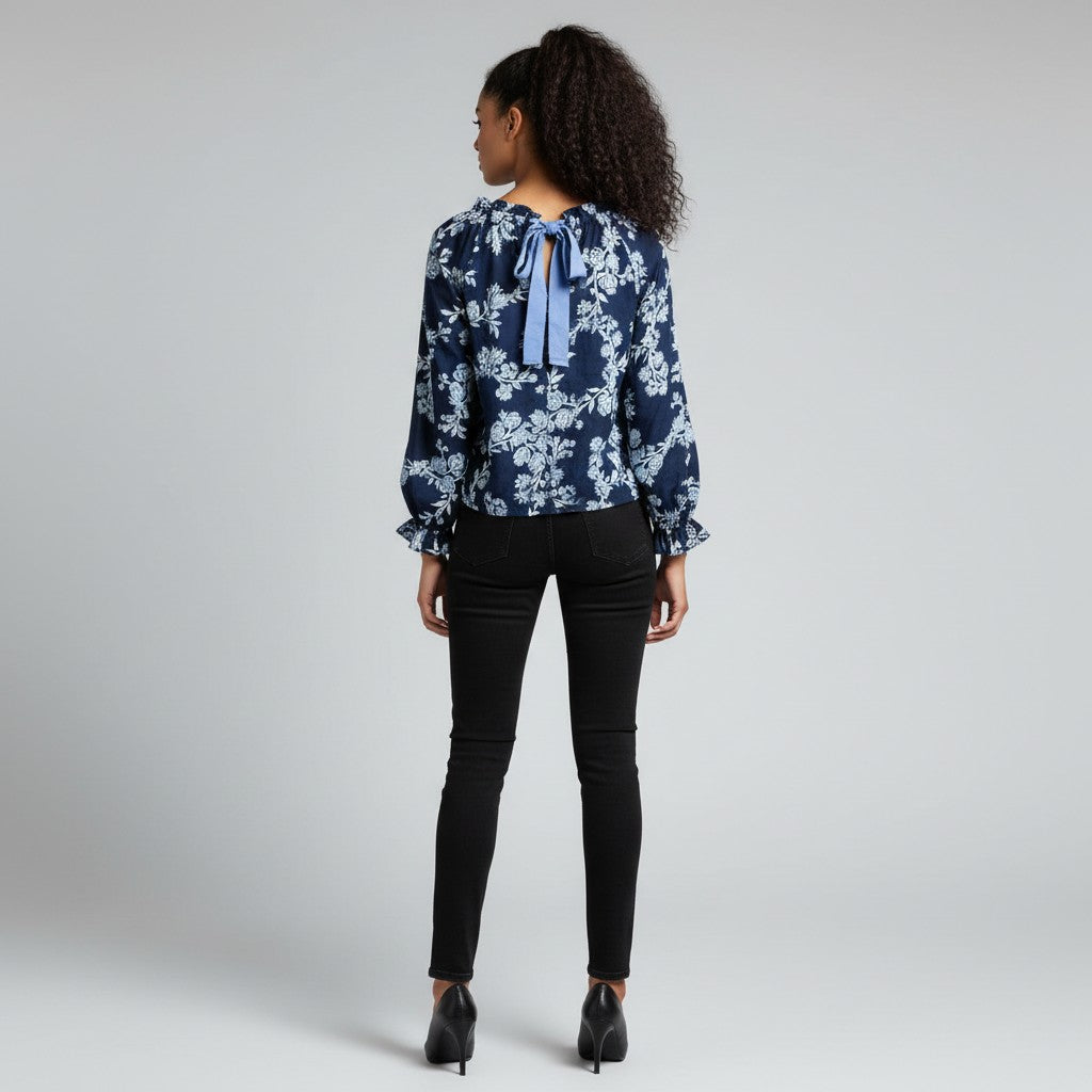 A woman with a blue and navy long sleeve shirt , black jeans , black high heels on a studio gray background.