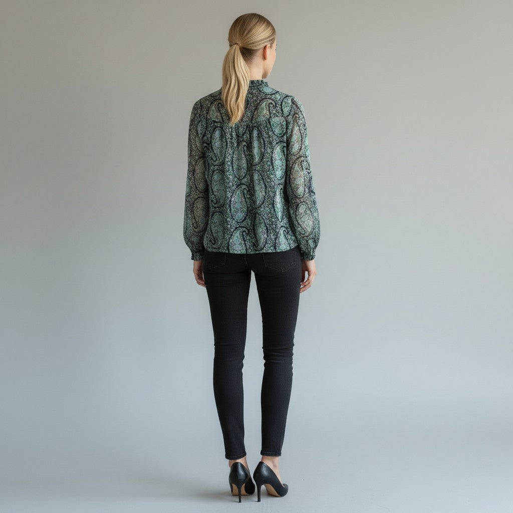 A woman wearing a floral top, black skinny jeans, black high heels on a studio background
