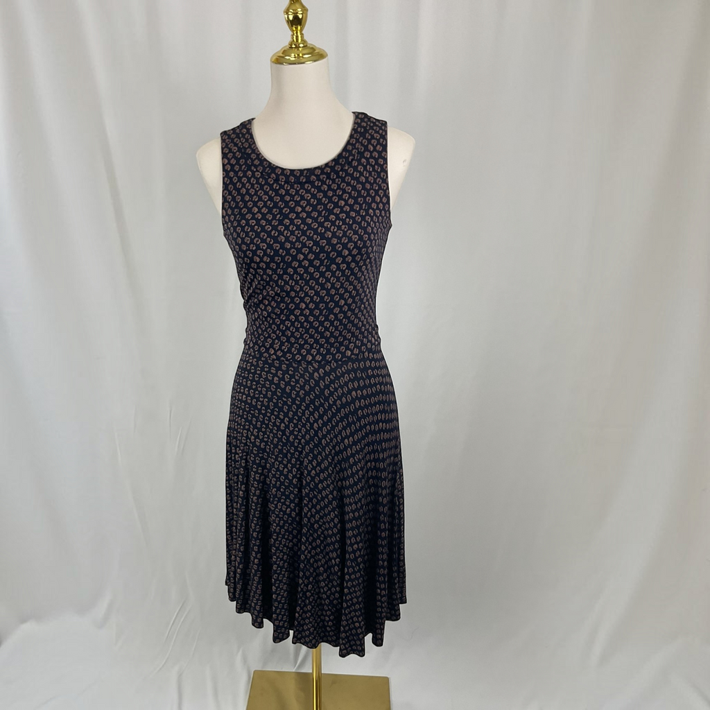 A sleeveless fit-and-flare dress with a small repeating geometric pattern in dark navy and pink, displayed on a white mannequin with a gold finial against a white fabric backdrop.