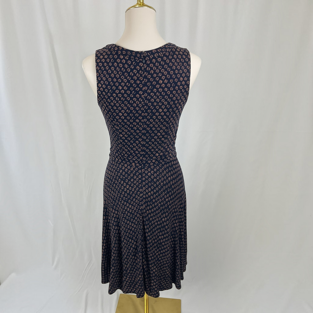 A sleeveless fit-and-flare dress with an allover small floral pattern, displayed on a mannequin torso against a white fabric backdrop.
