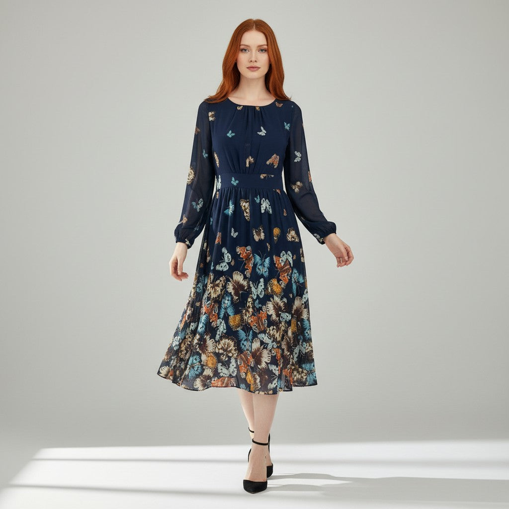 A woman modeling a long-sleeve midi dress with a dark navy base and a colorful butterfly and floral print, set against a neutral light gray studio background.