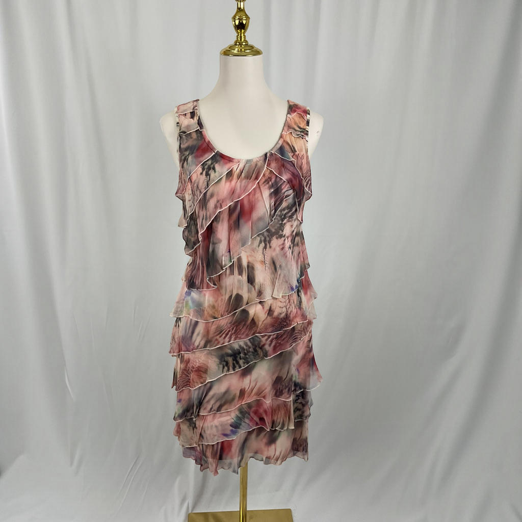 A sleeveless ruffled mini dress with an abstract watercolor print in pink, red, gray, and black, displayed on a white mannequin torso with a gold stand against a white draped fabric background.
