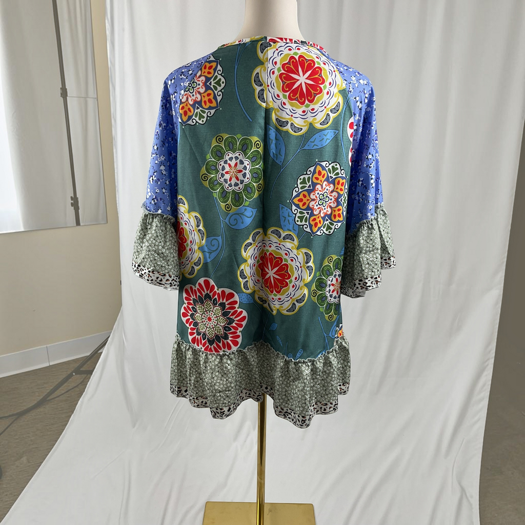 A woman wearing a floral shirt, white jeans, white sandals on a studio gray background,