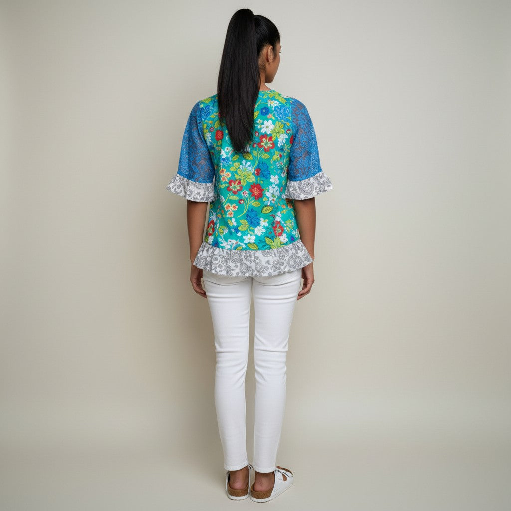 A woman wearing a floral shirt, white jeans, white sandals on a studio gray background,