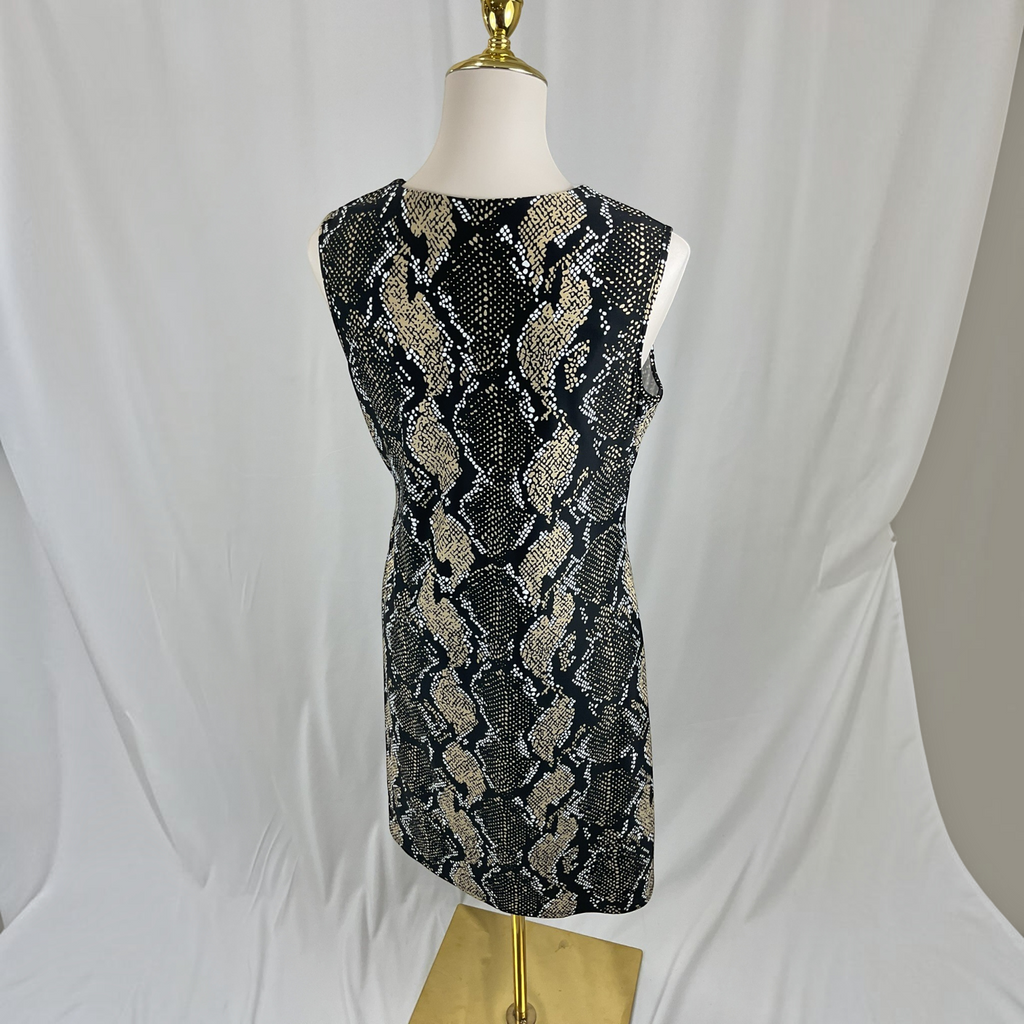 A sleeveless bodycon dress with a black and beige snakeskin pattern, displayed on a cream mannequin with a gold base against a draped white fabric backdrop.