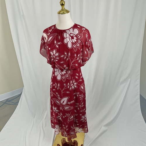 A red midi dress with a white floral pattern, displayed on a mannequin against a white fabric backdrop.