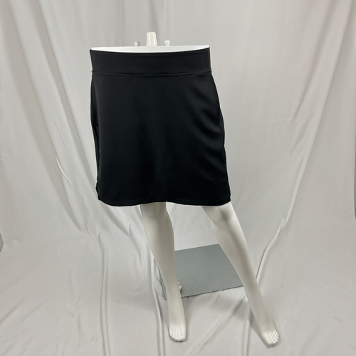 A black athletic skirt displayed on a white mannequin lower body against a white draped fabric backdrop.