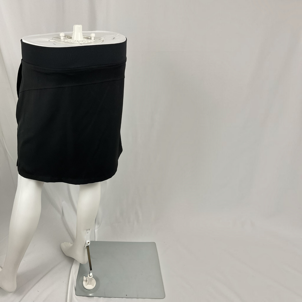 A black athletic mini skirt displayed on a white mannequin torso and legs against a white studio backdrop.