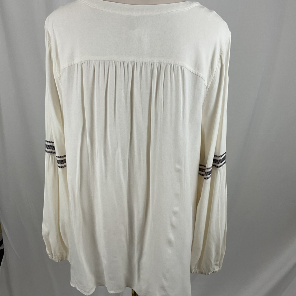 An off-white long-sleeve blouse with a gathered yoke and striped detailing on the sleeves, shown on a mannequin against a light gray backdrop.