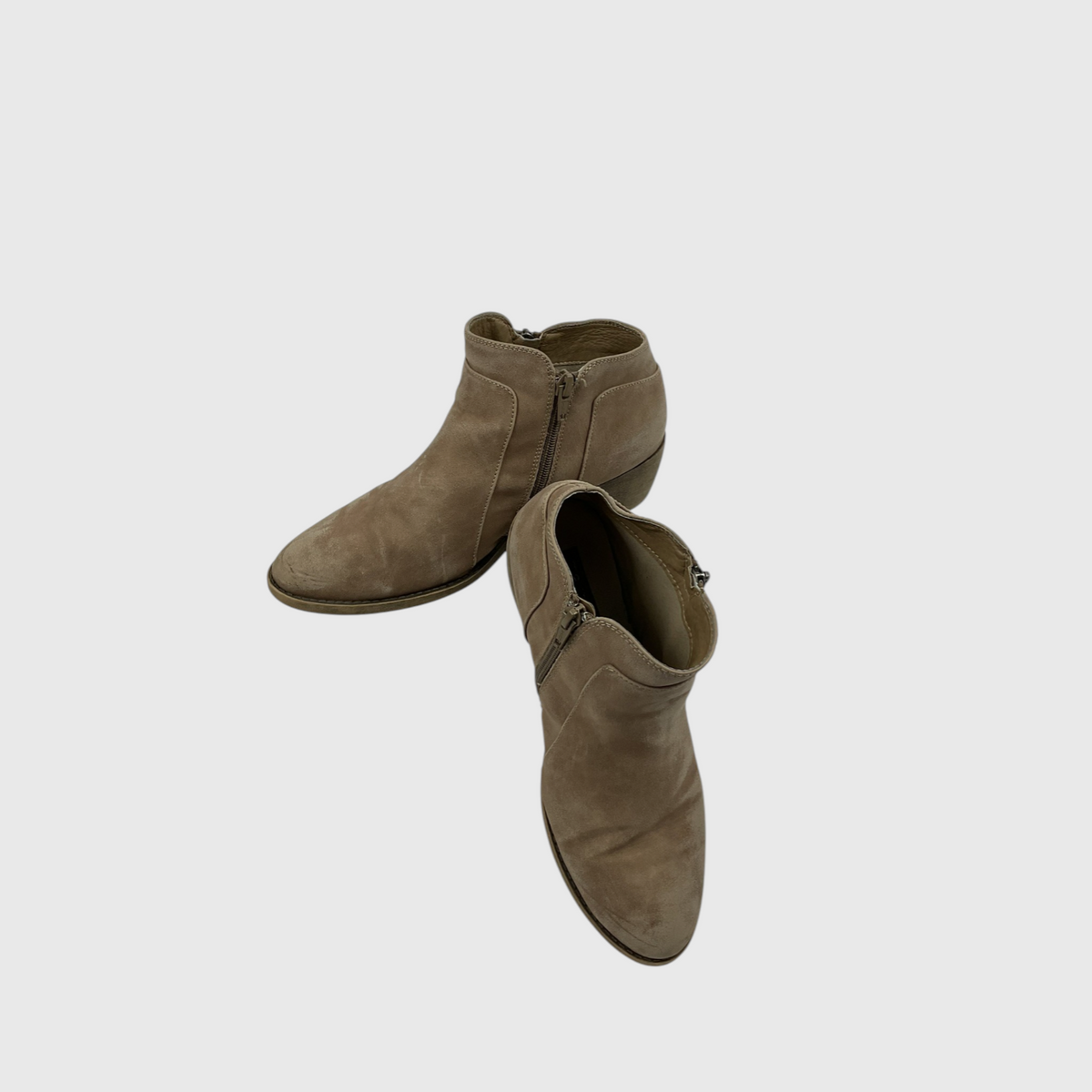 A pair of taupe-brown suede ankle boots with side zippers, shown from a top-down angle on a light gray background.