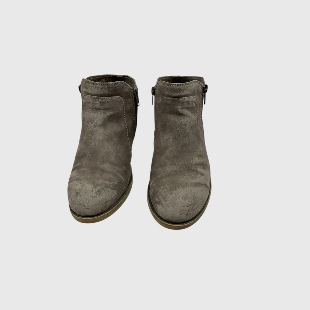 A pair of taupe-brown suede ankle boots with side zippers, shown from a top-down view on a light gray background.