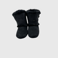 A pair of black suede winter boots with fluffy black faux-fur trim at the top and around the ankle, shown against a solid light gray background.