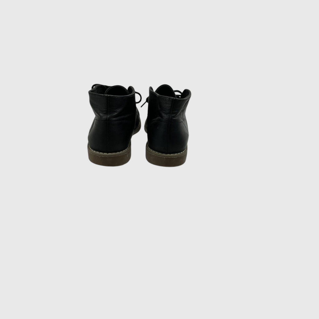 A pair of black leather ankle boots shown from the back, featuring black laces and brown soles, set against a solid light gray background.