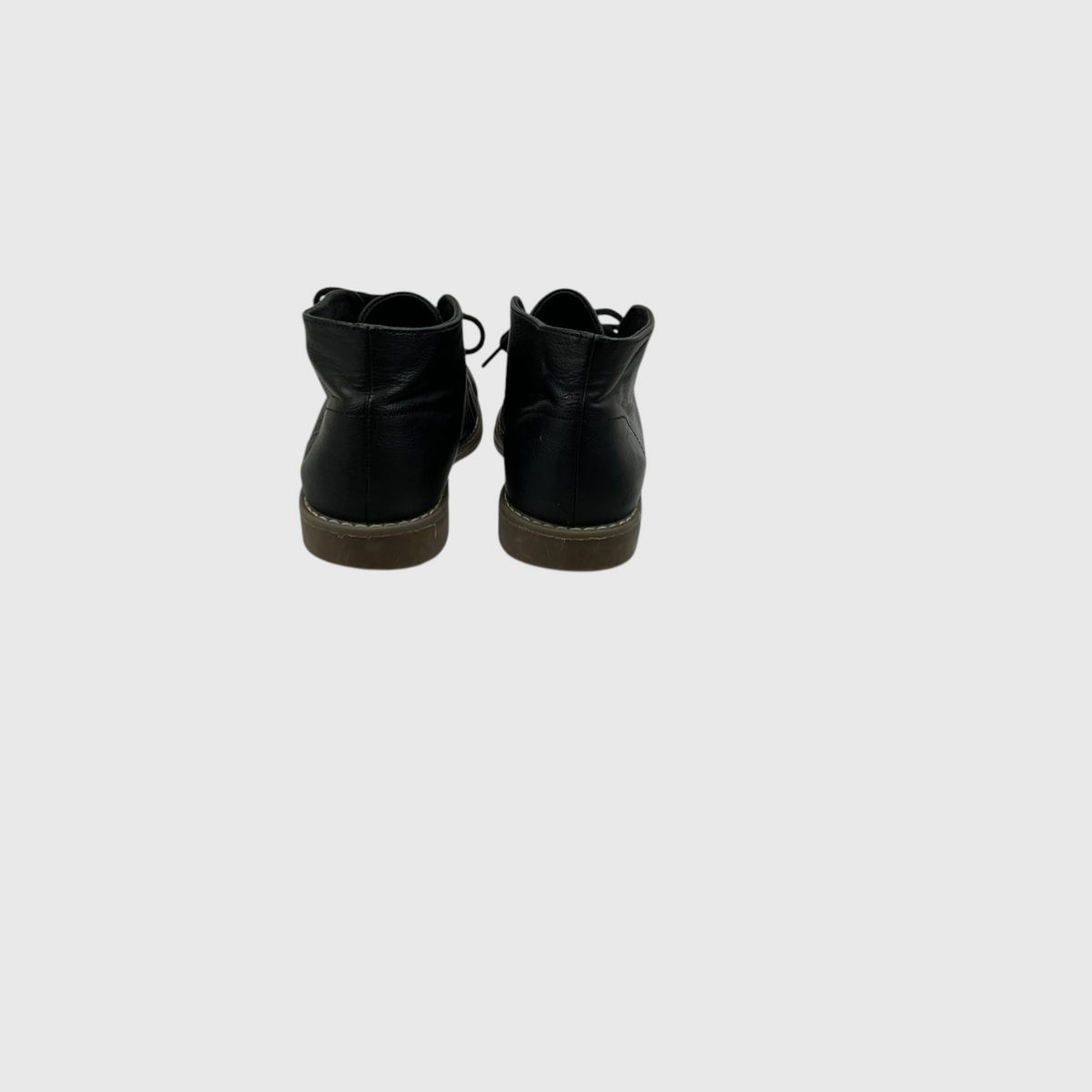A pair of black leather ankle boots shown from the back, featuring black laces and brown soles, set against a solid light gray background.