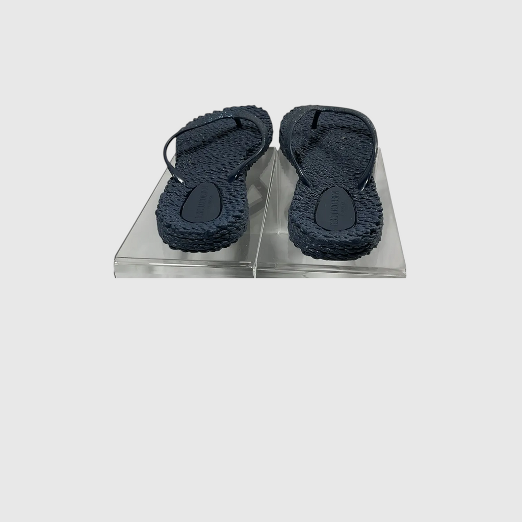 A pair of textured navy blue flip flops on a light gray background.