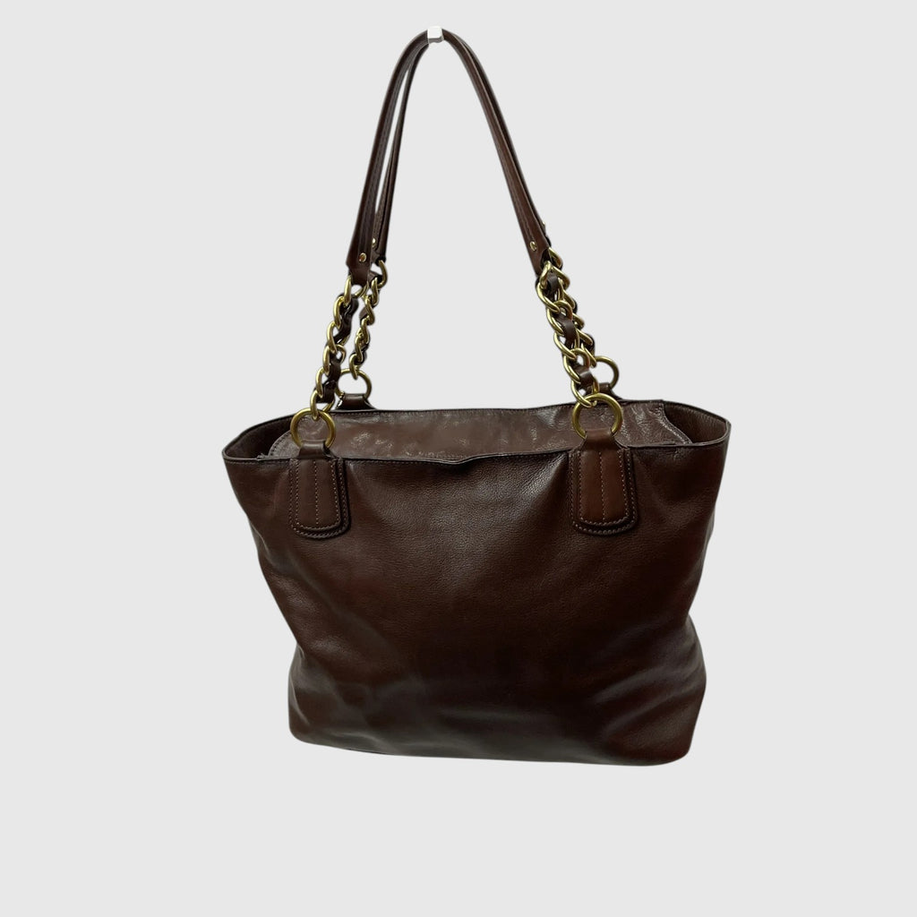 A dark brown leather tote bag with gold-tone chain details on the shoulder straps, shown against a plain light gray background.